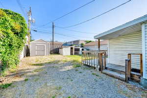 Fenced backyard featuring a storage shed and a wooden deck