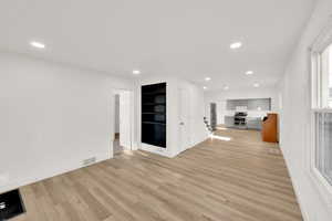 Unfurnished living room with light wood-style flooring, recessed lighting, and built in shelves