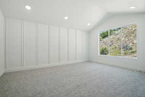 Empty room with light colored carpet, vaulted ceiling, recessed lighting, and baseboards