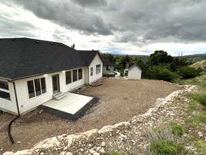 Back of house with a shingled roof, stucco siding, and a patio area
