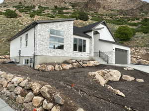 View of front facade with stone siding, driveway, stucco siding, a garage, and a mountain view