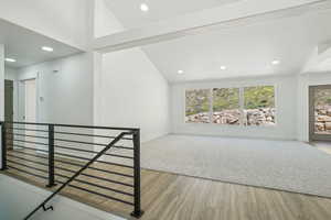 Empty room featuring wood finished floors, baseboards, vaulted ceiling, and recessed lighting