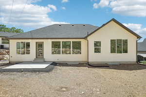 Rear view of house with a shingled roof, a patio, stucco siding, and entry steps