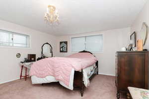 Carpeted bedroom featuring a textured ceiling, baseboards, and a chandelier