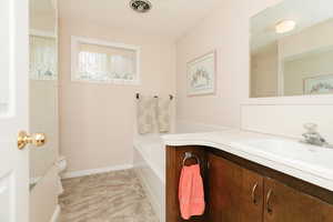 Bathroom featuring vanity, toilet, baseboards, and a bathtub