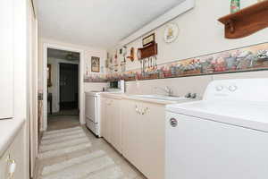 Laundry room with cabinet space, a textured ceiling, light tile patterned floors, and washing machine and dryer