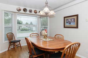 Dining room featuring healthy amount of natural light, light wood-type flooring, baseboards, and a textured ceiling