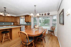 Dining room with a chandelier, light wood-style floors, a textured ceiling, and baseboards