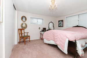 Bedroom featuring light colored carpet, a chandelier, and a textured ceiling