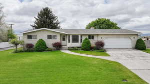 Single story home featuring a garage, concrete driveway, a chimney, and brick siding