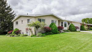 View of front facade featuring an attached garage, a front lawn, concrete driveway, and brick siding