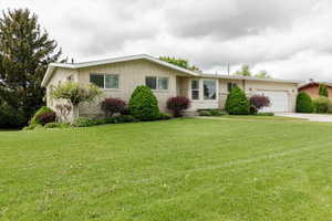 Ranch-style house featuring driveway, a garage, a front yard, and brick siding