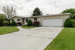 Single story home featuring brick siding, an attached garage, concrete driveway, and a front yard