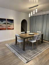 Dining area featuring arched walkways, wood finished floors, and baseboards