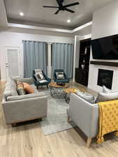 Living area with a tray ceiling, ceiling fan, wood finished floors, recessed lighting, and built in shelves