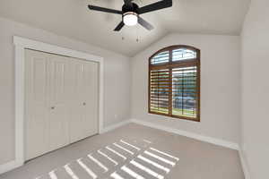 Unfurnished bedroom with carpet flooring, lofted ceiling, baseboards, and a closet