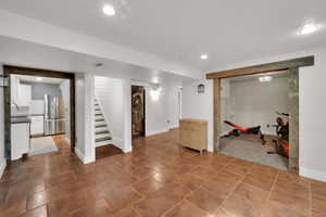 Finished basement with freestanding refrigerator, stairs, recessed lighting, and baseboards