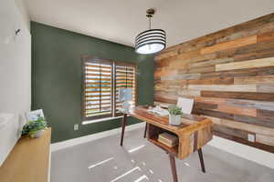 Home office featuring wood walls, carpet flooring, and baseboards