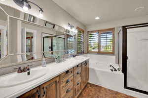 Bathroom with a shower stall, double vanity, a bath, and recessed lighting