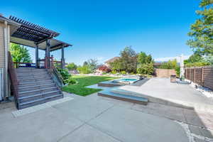 View of patio with an in-ground hot tub and a pergola