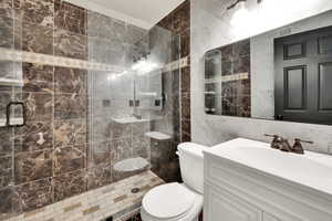Bathroom featuring tile walls, a stall shower, vanity, and toilet
