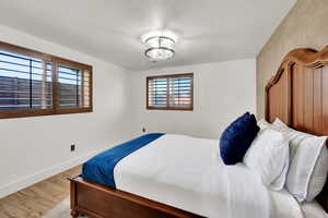 Bedroom with wood finished floors, baseboards, and a textured ceiling