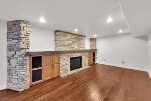 Unfurnished living room featuring a fireplace, baseboards, wood finished floors, and recessed lighting