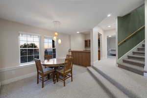 Dining room with light carpet, recessed lighting, stairs, and baseboards