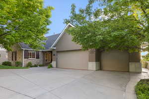 View of front of property featuring stone siding, driveway, stucco siding, and an attached garage