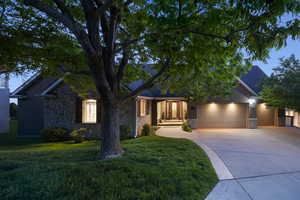 Ranch-style home featuring stone siding, driveway, a garage, and a front lawn