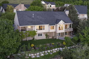 Rear view of house featuring a chimney, stucco siding, roof with shingles, and a patio
