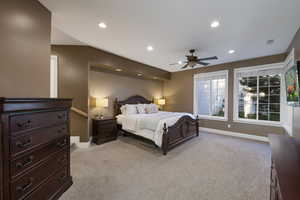 Primary bedroom with light colored carpet, baseboards, recessed lighting, multiple windows, and ceiling fan