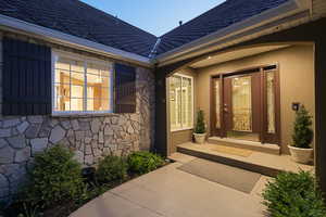 Doorway to property featuring stone siding and stucco siding