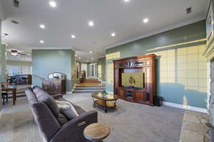 Carpeted living room with recessed lighting, ornamental molding, baseboards, ceiling fan, and stairs