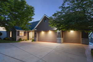 View of front of home with a garage, concrete driveway, stone siding, and stucco siding
