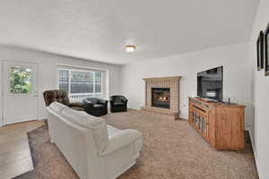 Living area featuring a textured ceiling, a brick fireplace, and light tile patterned floors