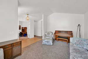 Sitting room with carpet floors, lofted ceiling, and baseboards
