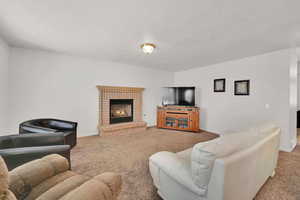 Carpeted living area featuring a textured ceiling, a fireplace, and baseboards