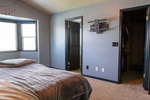 Primary Bedroom featuring a walk-in closet, carpet floors, lofted ceiling, a closet, and connected bathroom
