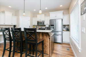 Kitchen featuring stainless steel appliances, backsplash, white cabinetry, and recessed lighting