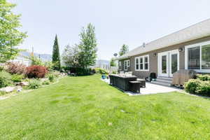 View of grassy yard featuring an outdoor living space, a patio area, a mountain view, and entry steps