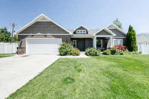 Craftsman house featuring an attached garage, driveway, and stone siding