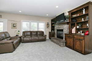 Living area featuring light colored carpet, a fireplace, plenty of natural light, and recessed lighting