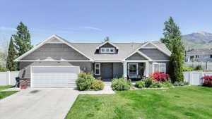 Craftsman house featuring stone siding, an attached garage, driveway, and a porch