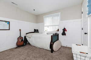 Carpeted bedroom with a decorative wall and wainscoting