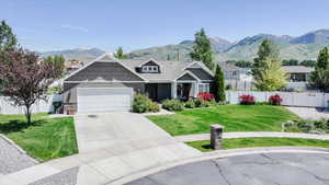 Craftsman-style home with an attached garage, a mountain view, driveway, and stone siding
