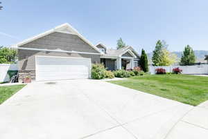 Craftsman-style house featuring a garage, driveway, and stone siding