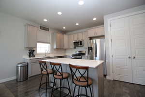 Kitchen with stainless steel appliances, a sink, a breakfast bar, LVP floors, and recessed lighting