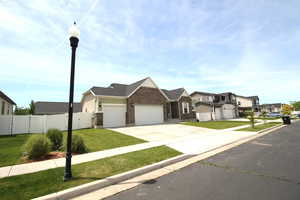 View of front of home featuring a residential view, an attached garage, driveway, brick siding, and a gate