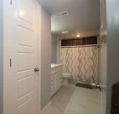 Full bath featuring marble finish floors, vanity, toilet, and a shower with curtain